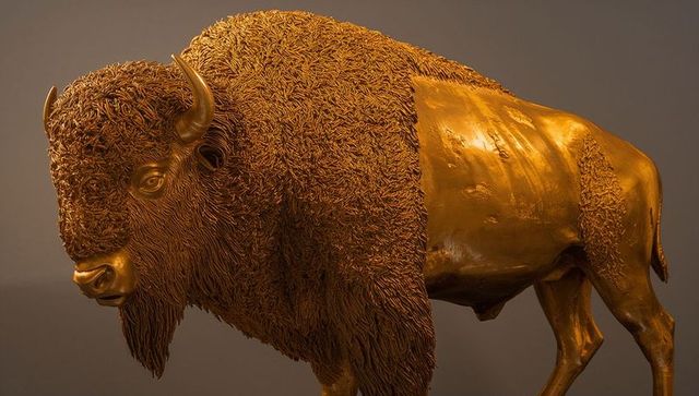 Bronze bison sculpture displaying textured mane and polished patina under gallery light