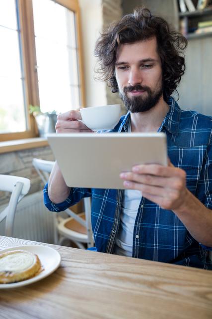 Man looking at digital tablet while having a cup of coffee in the coffee shop