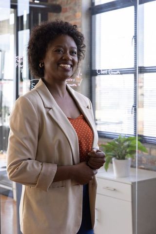 Confident Businesswoman Standing in Modern Office with Growth Diagrams