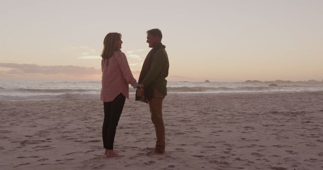 Happy senior caucasian couple holding hands on beach at sundown, copy space. Relationship, retirement, romance, vacations, nature, wellbeing and active senior lifestyle, unaltered.