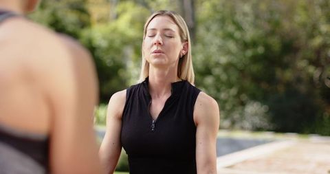 Women meditating poolside practicing mindfulness and relaxation outdoors