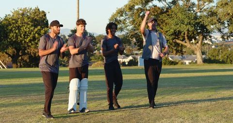 Young diverse cricket teammates celebrating victory while hoisting batsman in batting pads