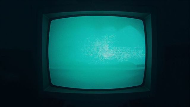 Teal glow vintage cathode ray tv in dark room