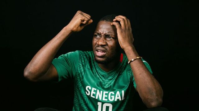 Frustrated senegal football fan clenching fist and grasping hair in green jersey reaction