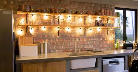 Glowing rustic industrial kitchen countertop with exposed brick and open wood shelves