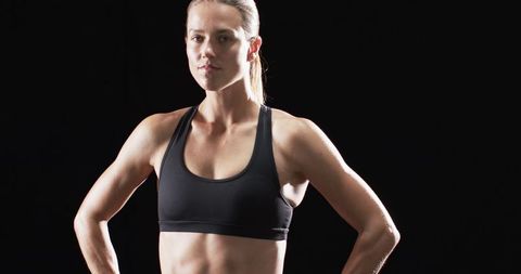 Confident Athletic Woman in Sports Bra Against Dark Background