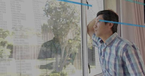 Asian teen gazing through glass door with data overlay reflecting quiet contemplation