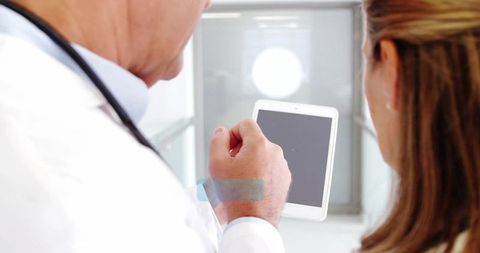 Doctor Guiding Senior Patient with Tablet in Modern Clinic Corridor