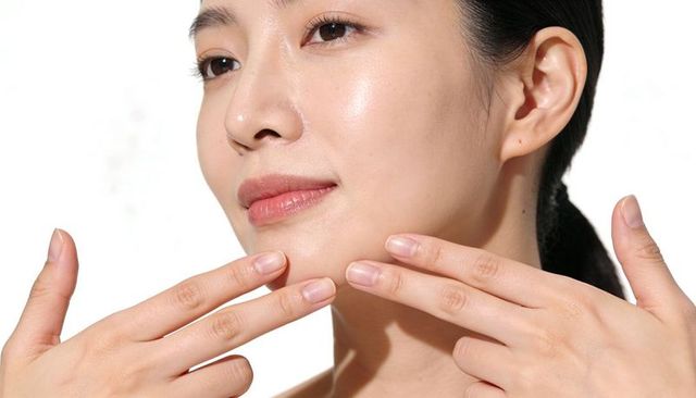 Asian woman touching glowing skin jawline skincare routine closeup portrait natural beauty