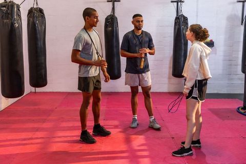 Teenage girl training with two male trainers in boxing gym holding jump ropes