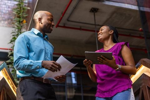 Coworkers Collaborating in Modern Industrial Workspace on Staircase Landing