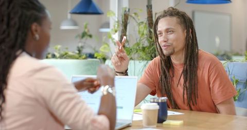 African American Coworkers Collaborating in Sunlit Green Coworking Lounge with Laptops