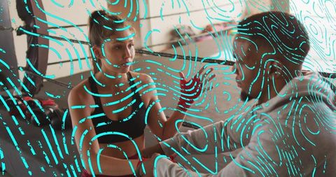 Female boxer training with coach holding focus mitts and throwing punches in gym