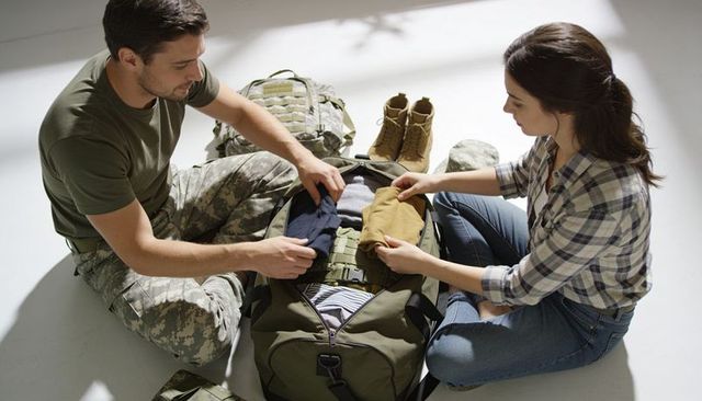 Couple packing tactical military duffel, organizing combat gear and boots before deployment