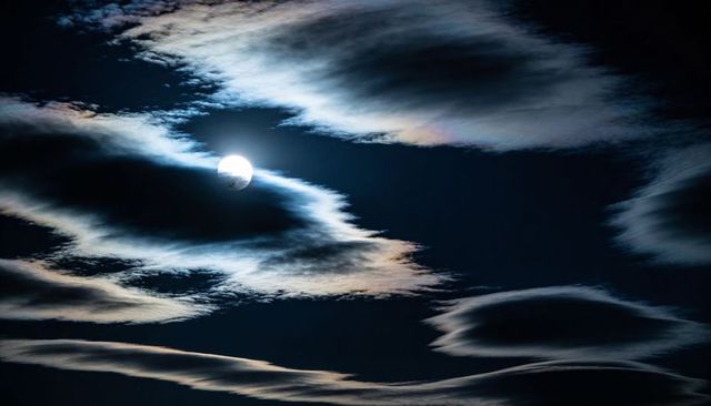 Moonlit Night with Iridescent Lenticular Clouds Creating Dramatic Lunar Halo Backlit Moon