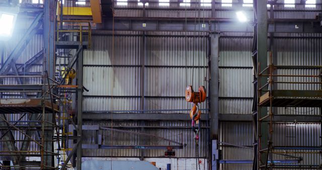 A crane hoists materials in an industrial warehouse setting. The machinery underscores the heavy-duty operations typical of manufacturing environments.