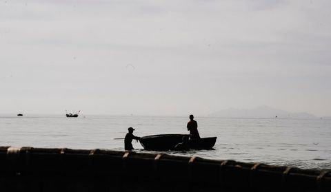 Silhouette fishermen on calm sea seascape view