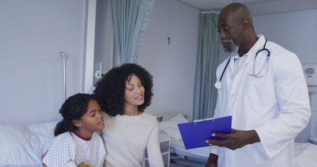 A doctor consulting with a mother and child in a hospital room. The doctor is showing a clipboard to the mother while the child stands beside her, looking on. This can be used for advertising healthcare services, promoting hospital facilities, or illustrating articles about medical consultations and family health care.