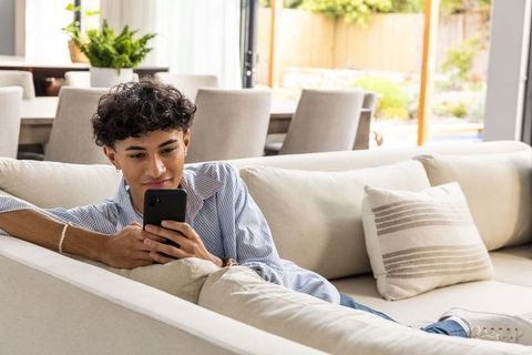 Young Man Relaxing on Sofa Scrolling Smartphone in Modern Living Room