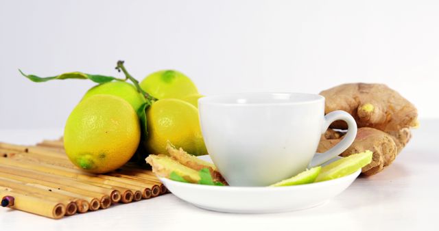 Fresh lemons and ginger with a white cup are placed on a bamboo mat. This setup evokes a sense of natural, healthy living. Can be used in articles and promotions related to holistic wellness, herbal teas, healthy diets, and clean eating.