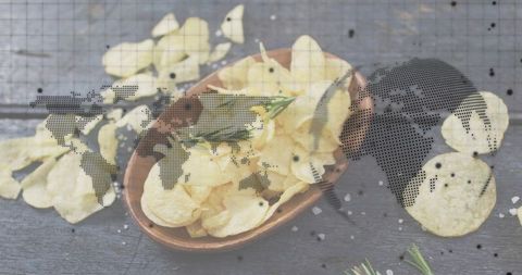Displaying rustic wood bowl with crispy potato chips, rosemary and sea salt over world map overlay