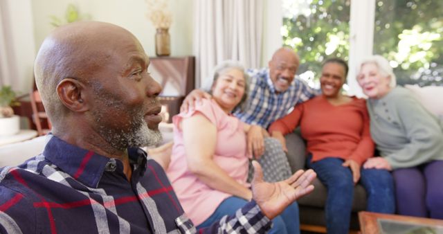 Group of seniors sitting together, smiling and enjoying each other's company in cozy home environment. Perfect for illustrating concepts of friendship, community, social bonding, and elderly lifestyle. Suitable for retirement community advertisements, social gatherings promotions, and articles on aging gracefully.