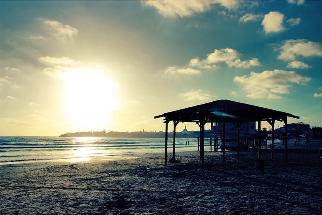 Sunset Over Sheltered Beach Structure with Clouds and Waves - Download Free Stock Photos Pikwizard.com