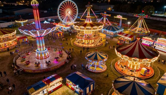 Glowing double-decker carousel lighting lively night carnival with ferris wheel