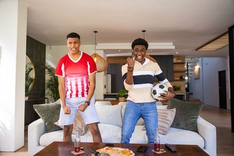 Friends cheering watching soccer match in modern living room