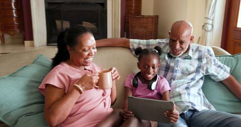 Senior African American Grandparents and Granddaughter Sharing Tablet at Home