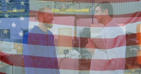 American flag overlaying workers discussing in factory