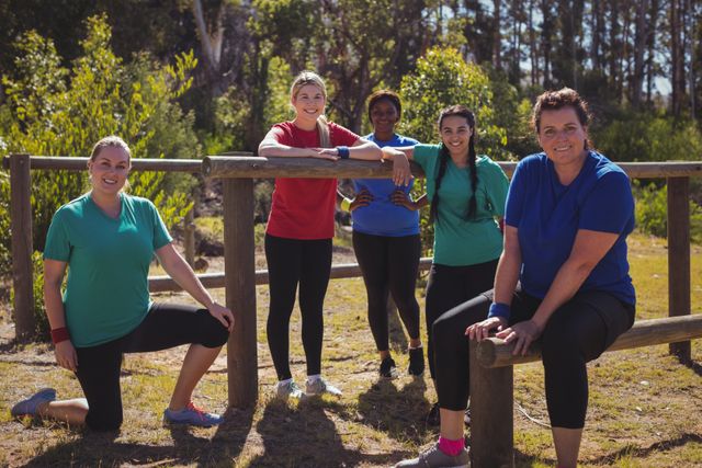 Group of fit women relaxing together at an outdoor boot camp on a sunny day. They are wearing sportswear and appear happy and energetic. This image can be used for promoting fitness programs, outdoor activities, team-building events, and healthy lifestyle campaigns.