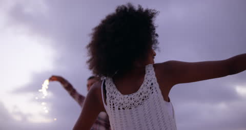 Joyful Couple Dancing with Sparklers at Dusk Beach