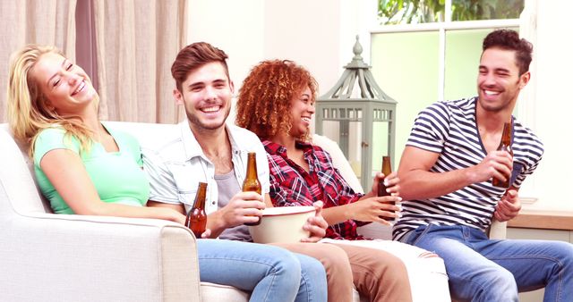 Group of young adults relaxing on a comfortable sofa at home, enjoying beverages and engaging in lively conversation. This image can be used for lifestyle blogs, social media, advertisement for drinks or social events, or articles about friendship and relaxation.