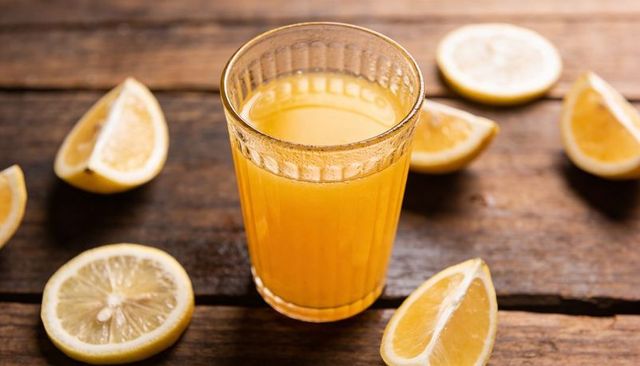 Fresh citrus juice in ribbed glass on rustic wooden table, bright summer drink