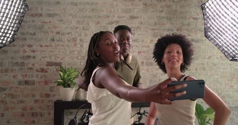 Young creators taking selfie in home podcast studio with softbox lights and mic arms