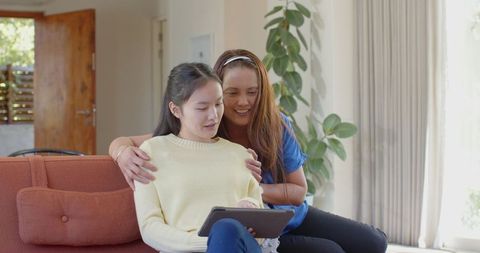 Asian Mother and Daughter Enjoy Quality Time Using Tablet at Home