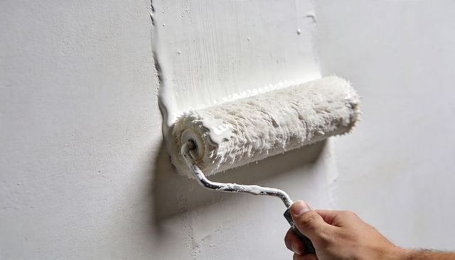 Hand Applying White Paint Roller on Interior Wall Showing Seam, Drips and Primer Texture