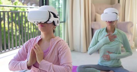 Diverse women practicing vr-guided meditation and mindful breathing on home yoga mats
