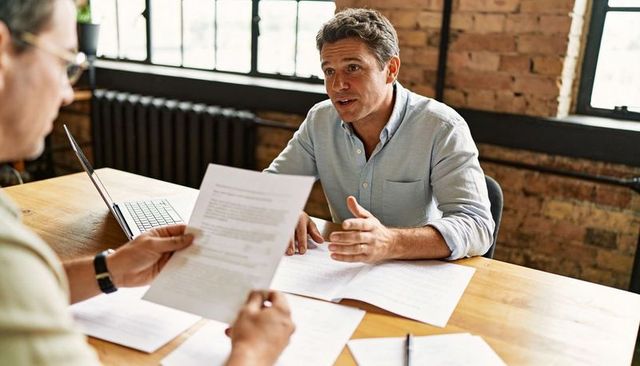 Manager discussing contract details with colleague in modern loft office meeting