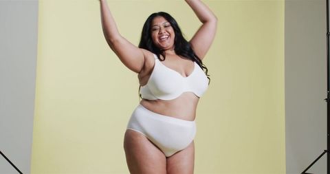 Confident Plus-Size Woman Posing Joyfully Against Yellow Background