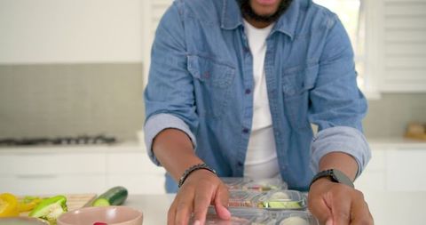 African american man prepping healthy meal prep containers on kitchen countertop