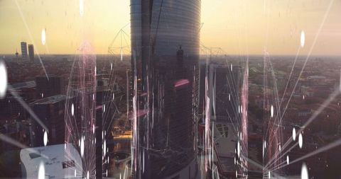 Futuristic glass skyscraper illuminated by sunset over city