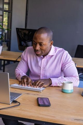 Professional Man Working on Laptop in Modern Open-Plan Office Setting
