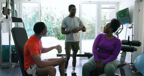 Friends Exercising Together in Home Gym Enjoying Conversation