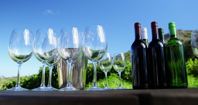 Close-up of wine glasses and bottles arranged on table in vineyard