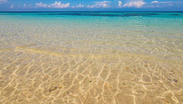 Sunlit shallow tropical lagoon with crystal clear water, sand caustics and turquoise horizon