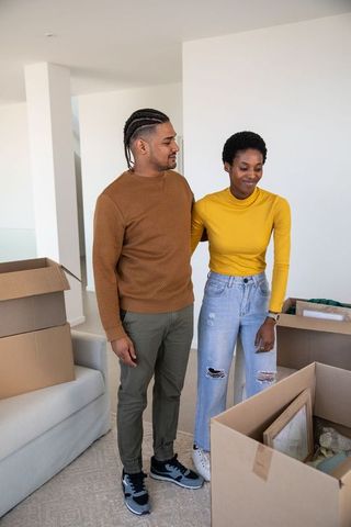 Diverse couple unpacking in new home with moving boxes