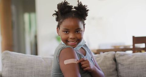 Young Girl Pointing at Bandage on Arm After Vaccination