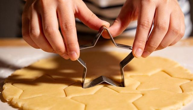 Child pressing star cookie cutter into dough for homemade baking and holiday treats